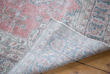 Folded Oushak rug revealing distressed raspberry pile and hand-knotted foundation.