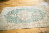 Distressed Oushak rug showcasing faded forest green field and terra cotta cranberry palmette border.