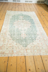 Distressed vintage Oushak rug close-up: forest green field, expressive lanterns, terra cotta cranberry border with palmettes.