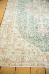 Distressed Oushak rug border with terra cotta cranberry palmettes, lotus flowers, and forest green field.