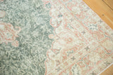 Distressed Oushak rug close-up, featuring worn palmettes on a cranberry border and green field.