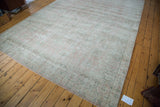 Distressed Oushak rug corner, soft sun-faded rose blush field, and mint celadon border.