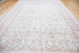Distressed Oushak rug with faded blush, soft green, ivory germinating floral pattern.