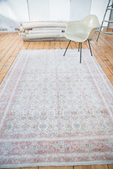 Distressed Oushak rug border with faded blush red and soft slate green motifs.