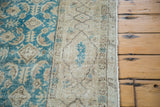 Textured detail of a distressed Oushak rug in teal and faded beige tones.