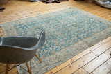 Distressed corner of a vintage teal Oushak rug, showing faded beige border and field patterns.