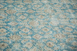 Distressed texture of a vintage Oushak carpet, showing faded teal and beige motifs.