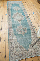 Distressed aqua blue Oushak runner showing ornate medallion with blush and ivory details.