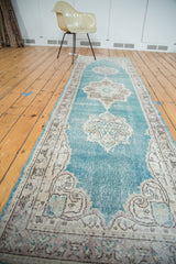 Ornate curvilinear border detail of a distressed aqua Oushak runner.
