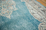 Distressed aqua blue field texture revealing foundation, with ornate ivory motif of Oushak runner.