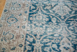 Distressed Oushak rug showing teal blue curvilinear blossoming floral pattern and faded pile.