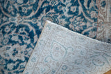 Distressed Oushak rug corner revealing dark teal curvilinear pile and hand-knotted woven foundation.