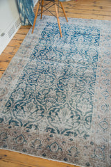 Distressed Oushak rug with decorative fading teal and beige curvilinear motifs.