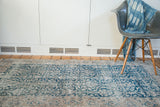 Distressed vintage Oushak rug featuring its faded dark teal blue curvilinear floral design.