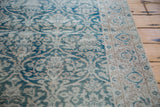 Distressed Oushak rug with faded teal curvilinear floral field and muted beige border.
