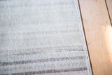 Distressed Oushak runner pile, showing soft horizontal stripes in neutral tones with a woven edge.