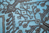 Hand-knotted tribal geometric motifs in charcoal black on a dense sky blue vintage rug.