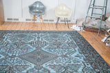 Overdyed carpet with a charcoal black tribal diamond medallion and sky blue field.