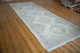 Angled view of distressed hand knotted Turkish Sparta runner, muted medallions in soft ivory and beige.
