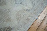Distressed hand-knotted pile with faded ivory, beige, and pewter medallions.