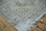 Distressed Sparta runner corner showing soft ivory, beige patterns, and fringed edge.