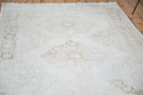 Distressed hand-knotted pile with faded ivory, beige, and coffee bronze medallion patterns.