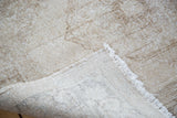 Distressed ivory and beige pile texture revealing the hand-knotted foundation and fringe.