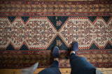 Distressed hand-knotted Malayer runner, showing geometric motifs in faded cinnabar red and navy blue.