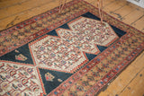 Angled close-up of the distressed Malayer runner's corner, showing faded geometric borders.