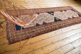 Distressed Malayer runner's geometric border in faded red, beige, and navy with fringe.