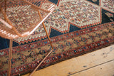 Distressed Malayer rug runner border, featuring faded floral motifs on a light bronze field.