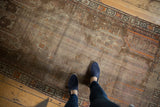 Distressed vintage Caucasian runner featuring faded brown field, geometric motifs, and orange accents.