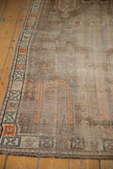 Distressed Caucasian runner showing worn pile, muted brown field, and geometric border.
