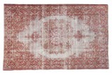 Distressed Sivas rug with a floral center medallion in faded cranberry red and grey on a worn foundation.