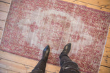 Overhead view of a distressed Sivas rug showing the faded cranberry red pattern and texture for scale.