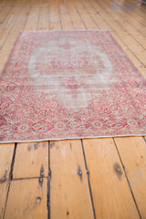 Low-angle perspective showing the distressed texture and cranberry floral border of a vintage Sivas rug.
