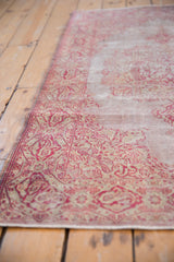Low angle view of a distressed Sivas rug showing its low pile and cranberry floral border.