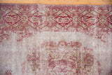 Aged texture of a distressed Sivas rug showing its exposed foundation and cranberry red design.