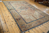 Vintage Kars carpet corner, deep indigo border, blush field, scrolling vines, feather leaves.