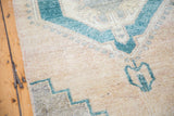 Mallard green octagonal and stepped patterns on a textured beige vintage Oushak runner.