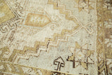 Distressed Oushak rug detail with geometric stepped and hook patterns in ivory, brown, and green.