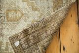 Distressed Oushak rug with ivory and pea green geometric pile showing its hand-knotted foundation.