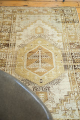 Distressed Oushak rug with decorative central tree motif and muted ivory brown texture.