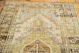 Distressed Oushak rug texture displaying geometric stepped patterns in soft ivory and natural brown.