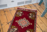 Vintage Oushak rug corner detail, with fringe, cherry red field, and mossy green tree motif.