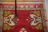 Vintage Oushak rug with cherry red field, ivory, grey blush, and mossy bronze tree motifs.