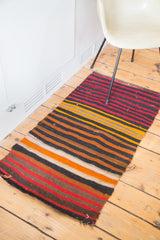 Hand-woven vintage Kilim rug end with bold horizontal stripes in red, orange, and black.
