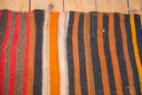 Hand-woven vintage Kilim rug shows textured horizontal stripes in red, tangerine, and dark navy.
