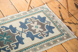 Vintage Oushak rug with geometric teal, navy, and brown motifs and meandering leaf border.