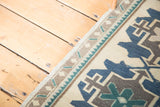 Hand knotted vintage Oushak rug showing teal, navy blue, brown geometric details and meandering border.